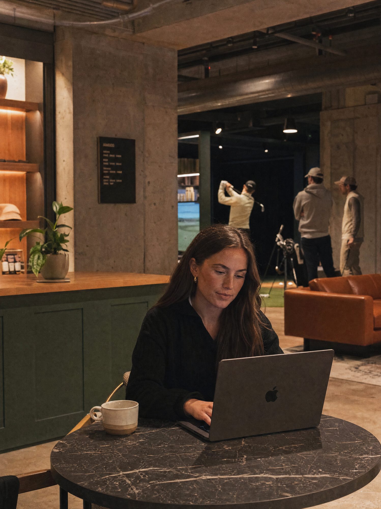 A venue operator working on a laptop beside the golf lounge